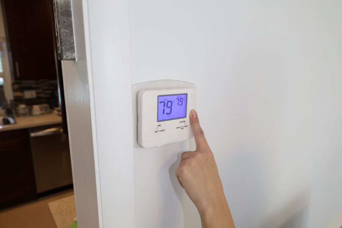 A person adjusting a thermostat.
