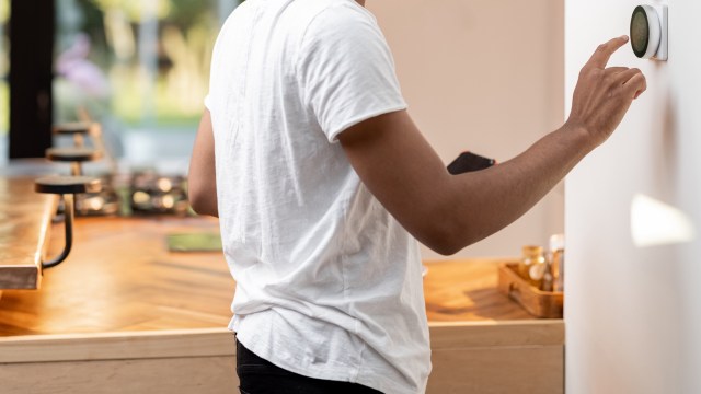 A person adjusting a thermostat.