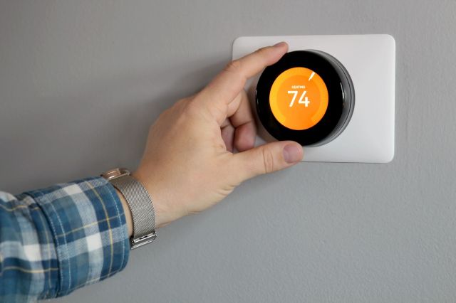 A person adjusting a thermostat.