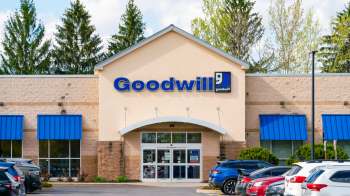 A Goodwill store with a blue awning and large glass entrance surrounded by parking.