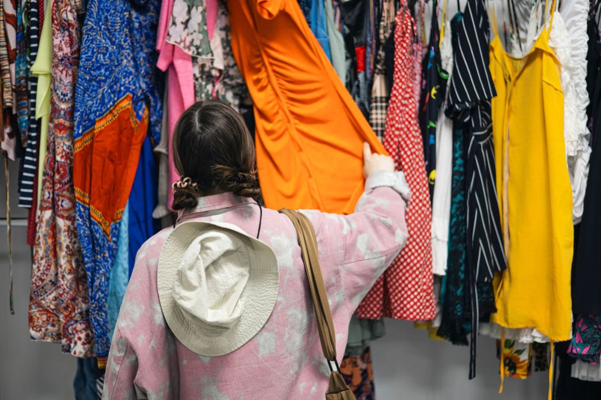 A woman looking through a clothes rack at a thrift store.