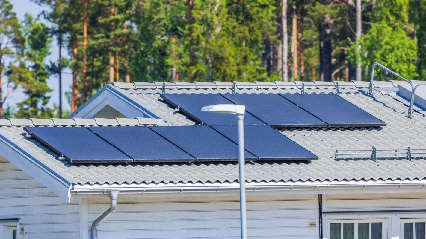A house with solar panels on the roof and trees in the background.