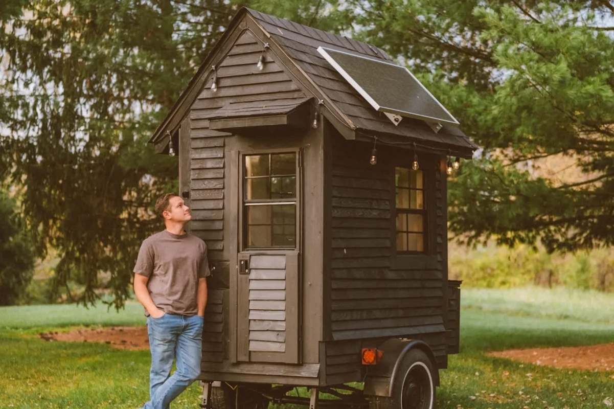 Levi Kelly beside his micro-house on wheels.