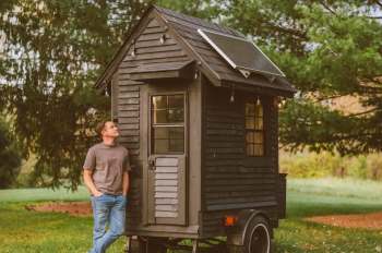 Levi Kelly beside his micro-house on wheels.