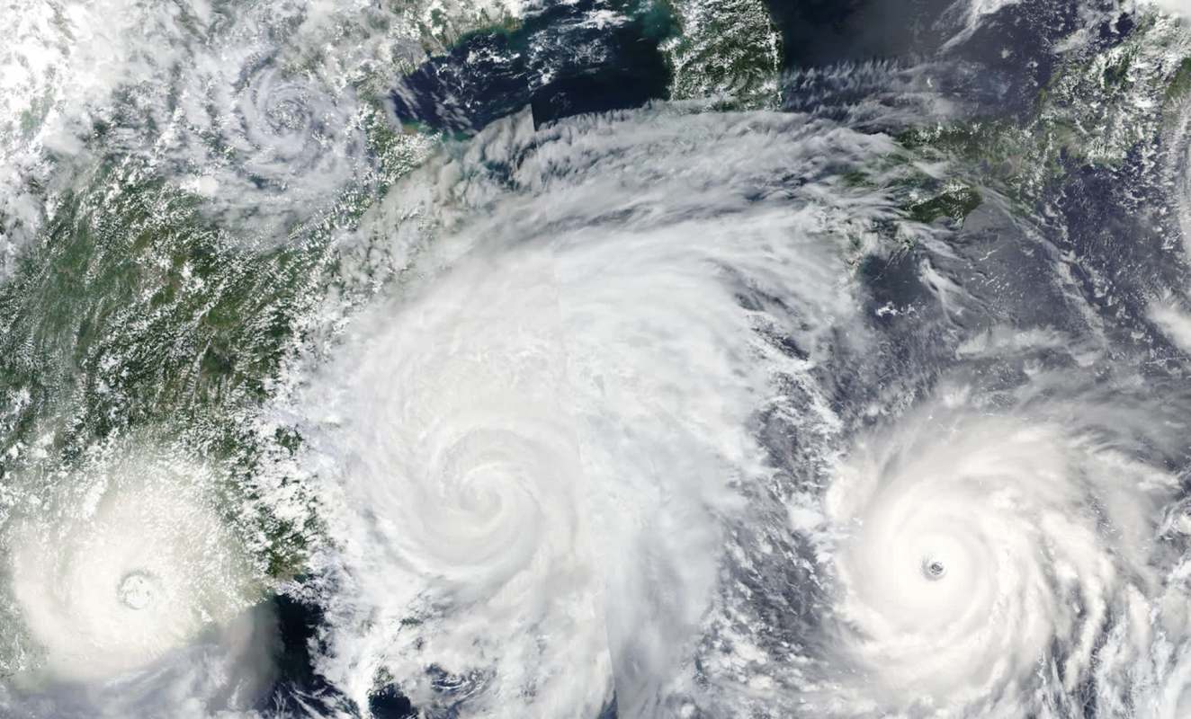 Three cyclonic storms are visible over land and ocean, surrounded by clouds.