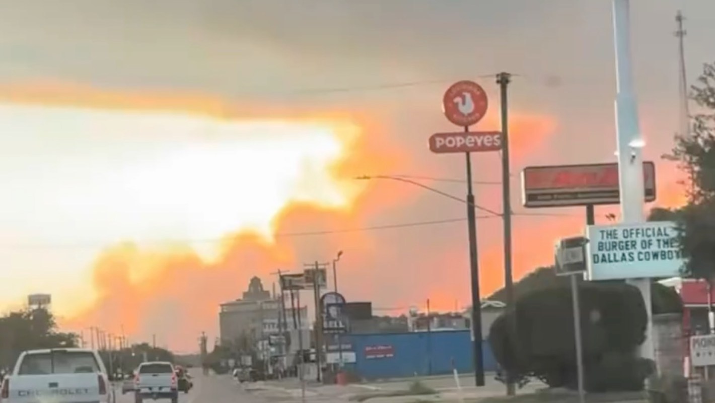 A city street view with a Popeyes sign and orange-ish wildfire smoke in the background.