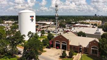 A water tower and a fire station are visible in a Texas town with various buildings and trees nearby.