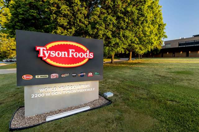 A sign for Tyson Foods headquarters with a logo and company information in a landscaped area.