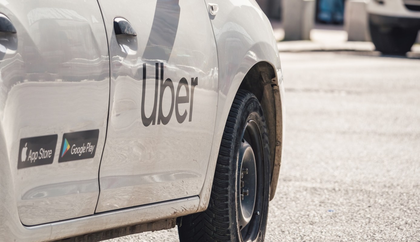 A close-up of the side of an Uber vehicle with app download icons.