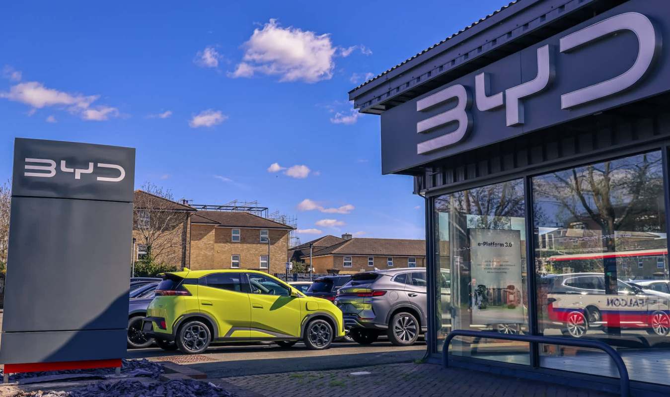 A BYD car dealership featuring a bright green vehicle outside and a large sign displaying the BYD logo.