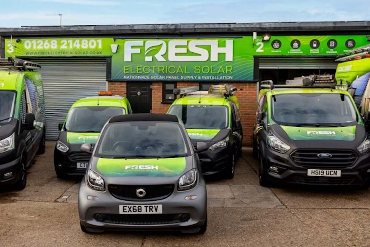 A lineup of vehicles in front of a building with a "Fresh Electrical Solar" sign.