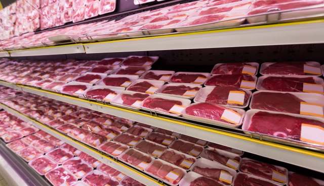 A display of packaged meat trays on supermarket shelves.