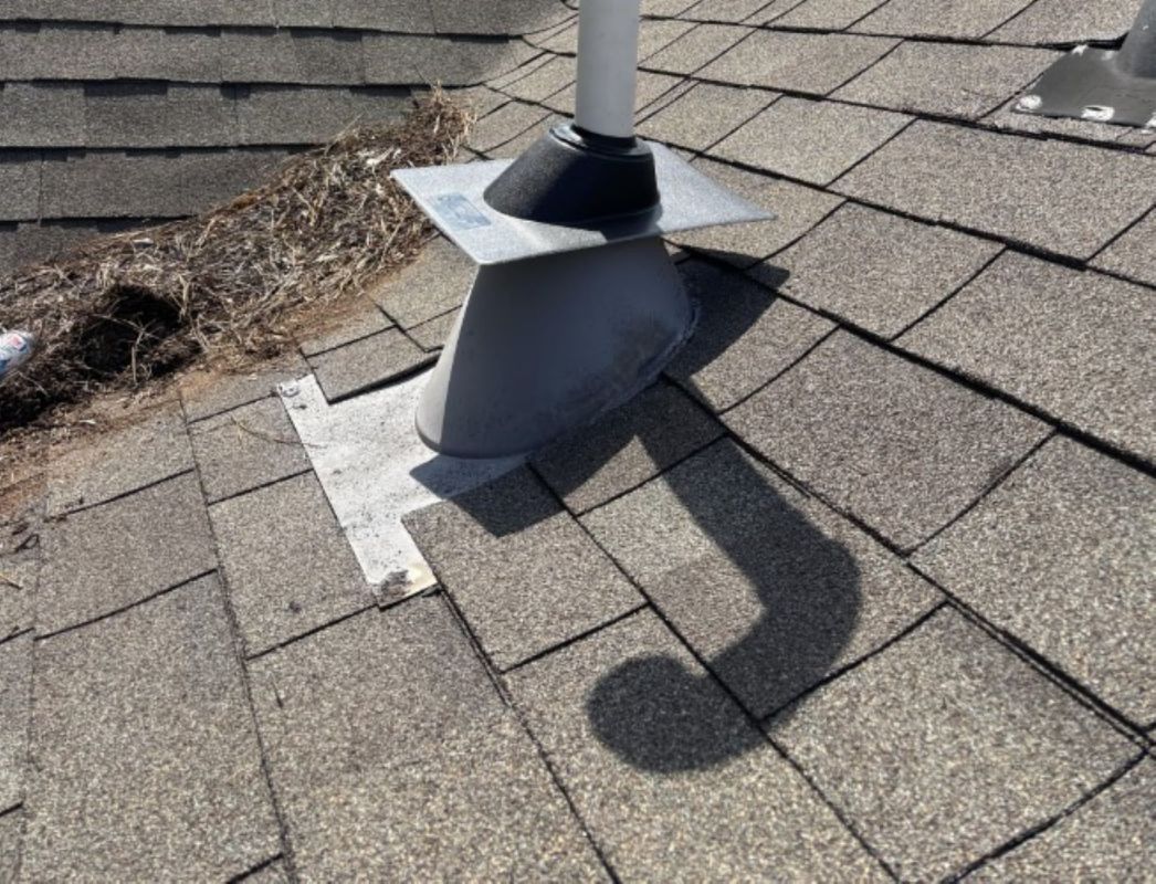 A vent pipe on a textured roof with visible debris and shadows.