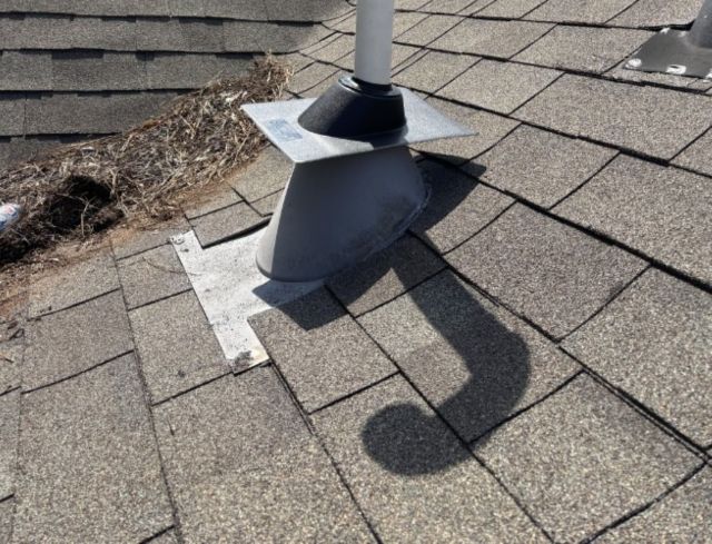 A vent pipe on a textured roof with visible debris and shadows.