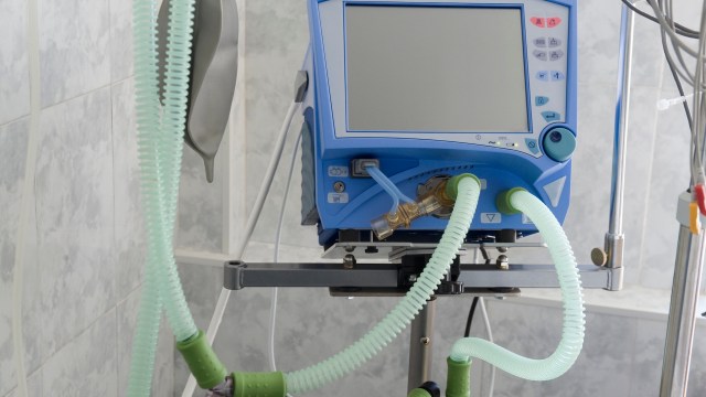 A medical ventilator with connected tubes in a clinical environment.