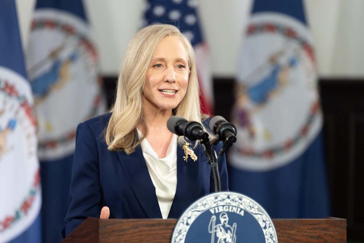 Virginia governor Abigail Spanberger speaks at a podium with the Virginia state seal and flags in the background.