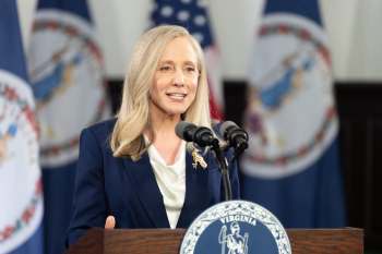 Virginia governor Abigail Spanberger speaks at a podium with the Virginia state seal and flags in the background.