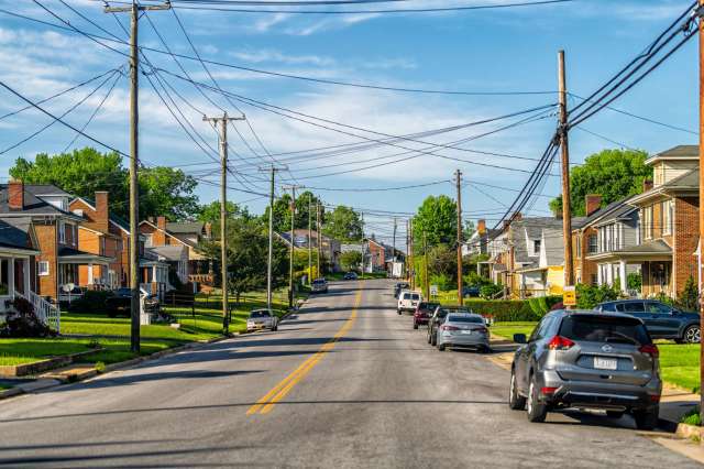A residential street lined with houses and utility poles under a clear blue sky.
