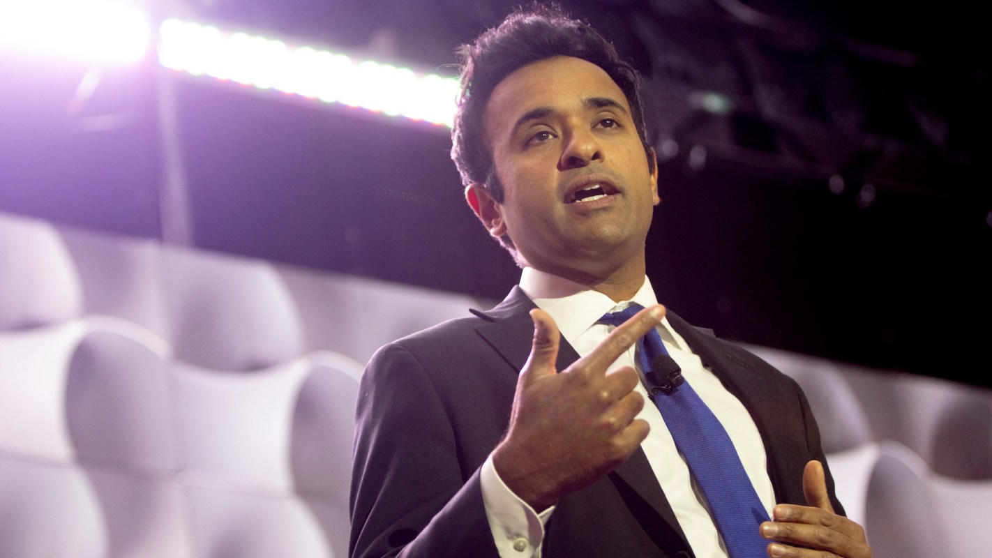 Vivek Ramaswamy gestures while speaking at a podium during an event.