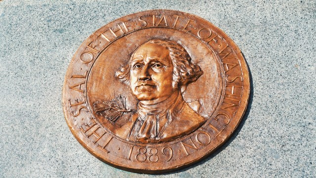 A bronze seal of the state of Washington featuring a portrait of George Washington.