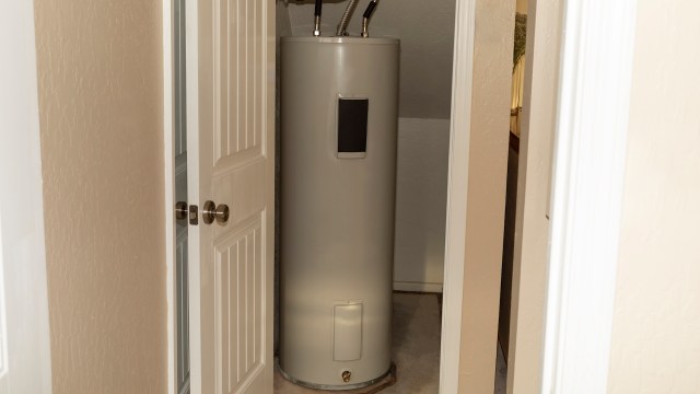 A water heater installed in a small closet space with white doors.