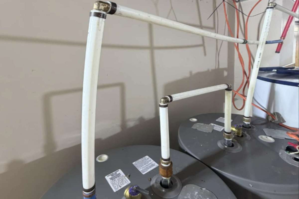 Pipes and valves connected to water heaters in a utility room.