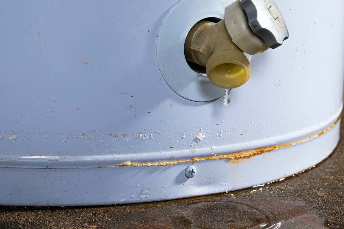 A leaking valve on a gray cylindrical container with water pooling beneath it.