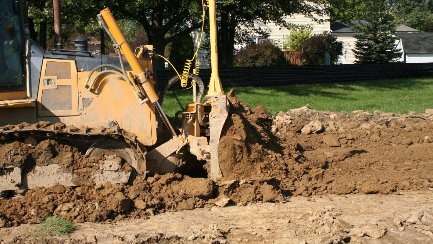 A bulldozer digs into the ground, creating a mound of dirt in a construction site.