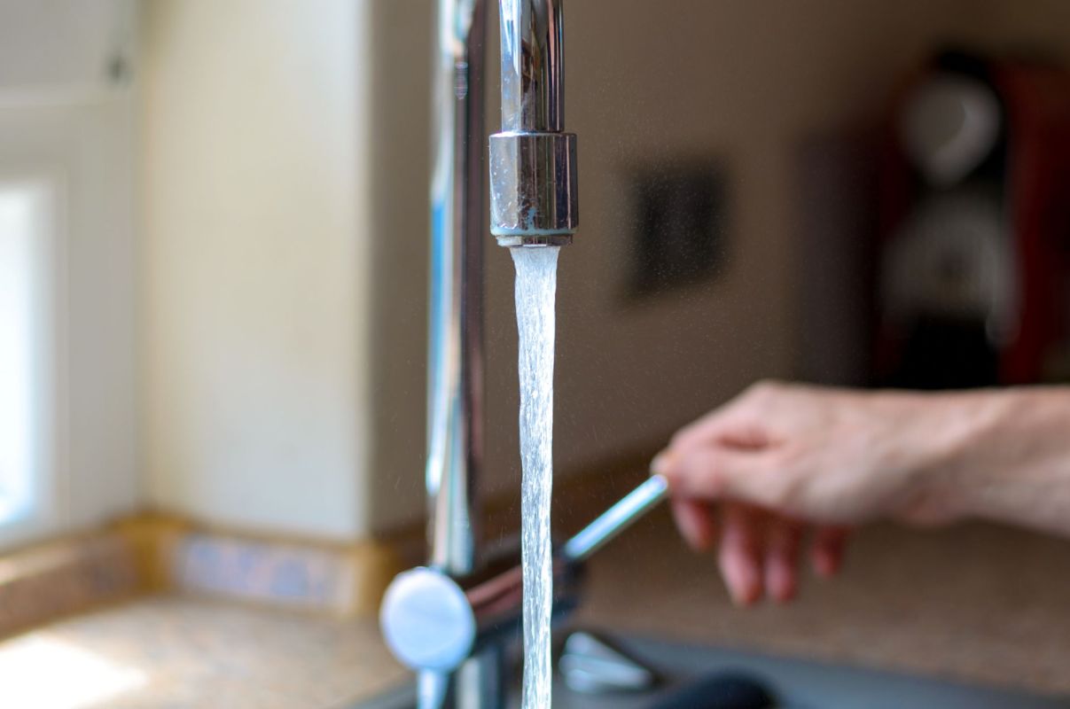 A person turning on the kitchen faucet.