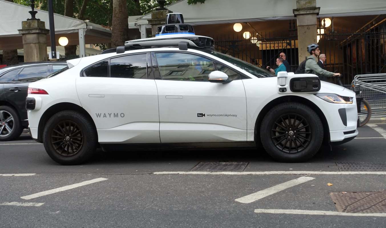 A white Waymo autonomous vehicle parked on a city street.
