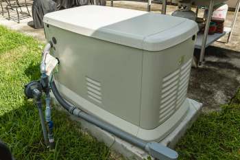 A home generator connected to plumbing surrounded by grass.