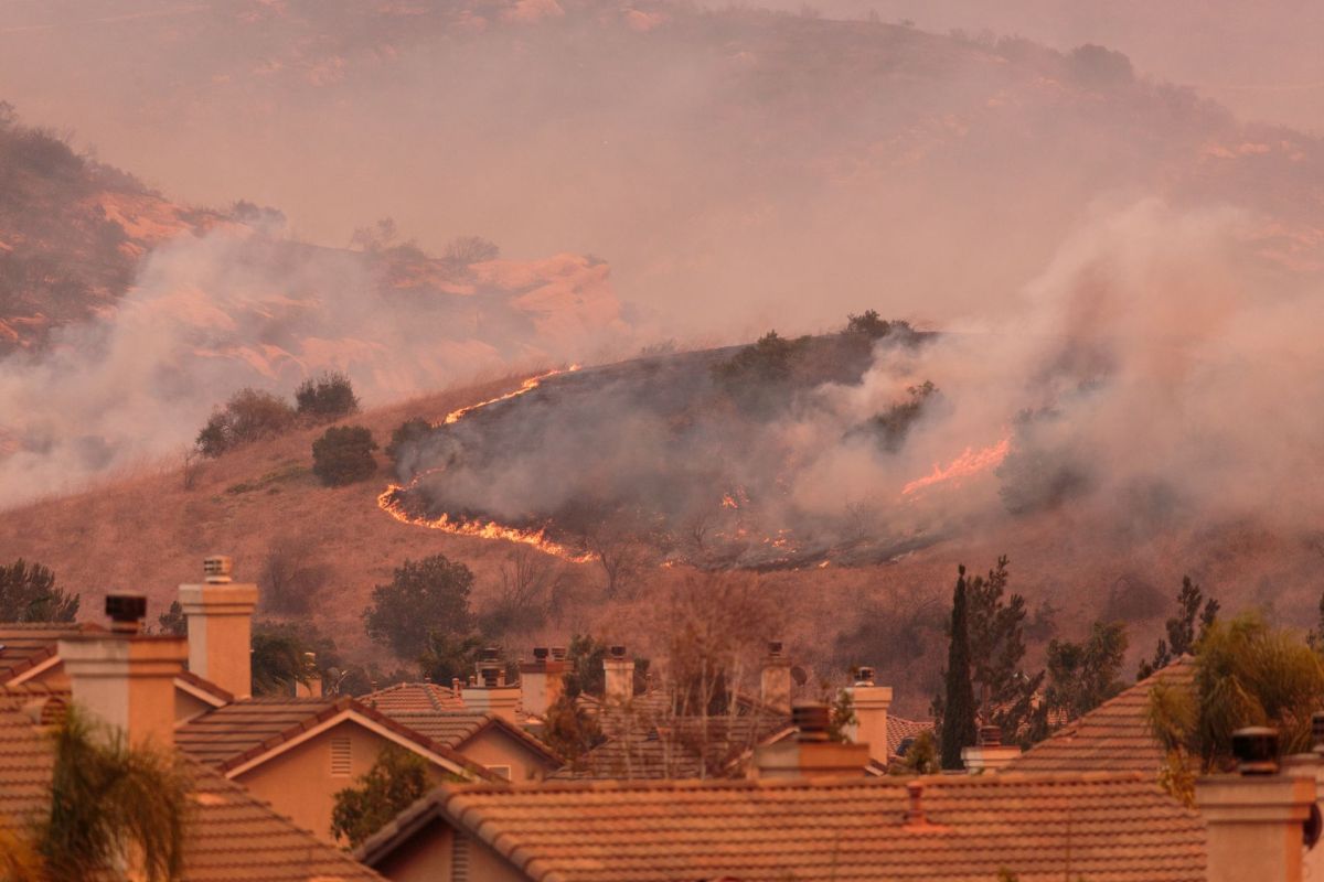 Wildfires burning behind homes.