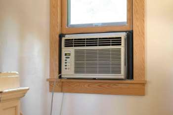 A window air conditioning unit installed next to a partially opened window.
