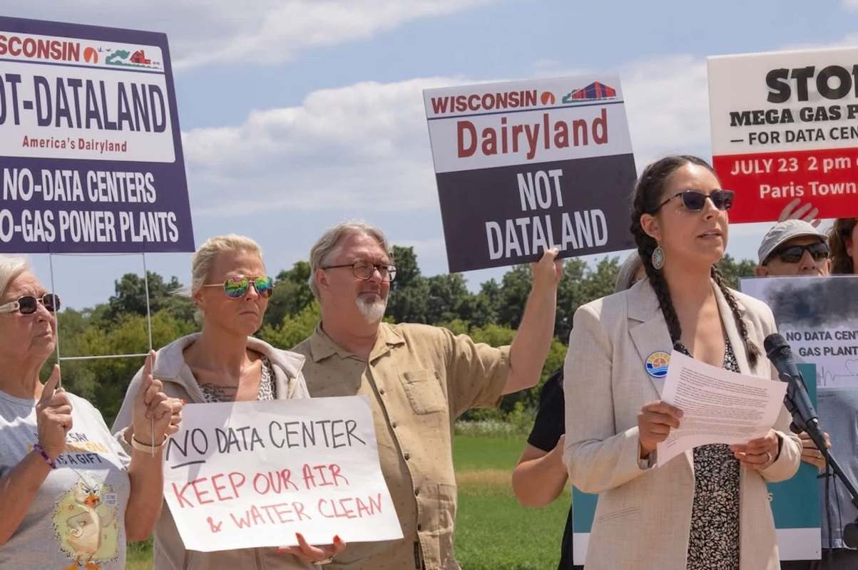 A group of people holds signs protesting against data centers and gas power plants.