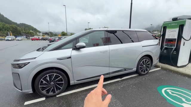 A silver electric vehicle at a charging station.