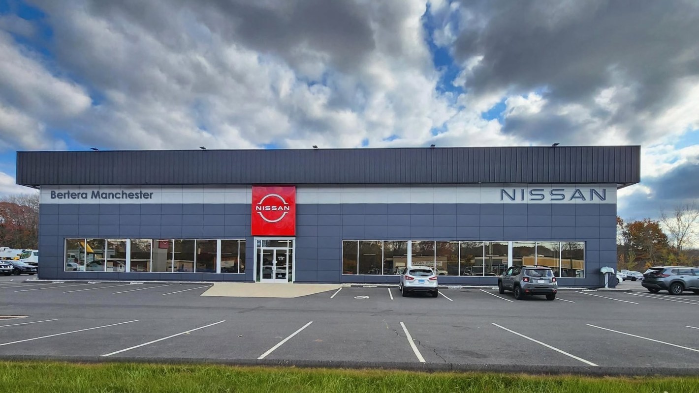A Nissan dealership with a modern building and several parked cars in the lot.