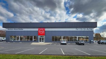 A Nissan dealership with a modern building and several parked cars in the lot.