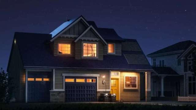 A house with illuminated windows and a starry night sky in the background.