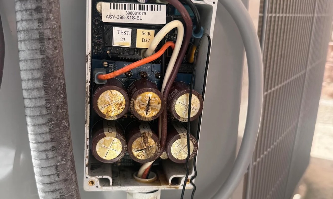 A close-up of an electrical component with several capacitors and wires inside a housing unit.