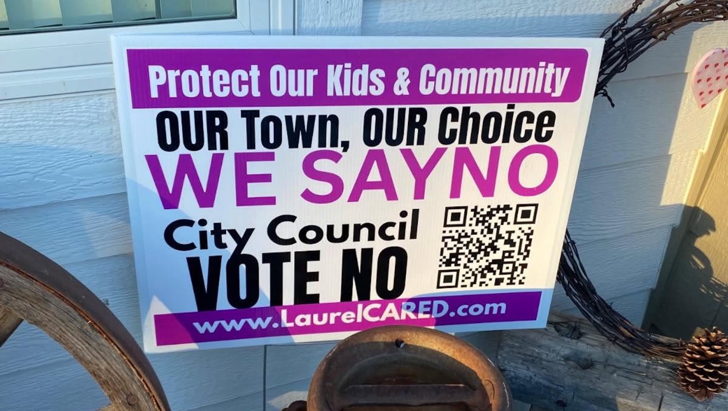 A yard sign advocating against a city council decision, featuring bold text and a QR code.