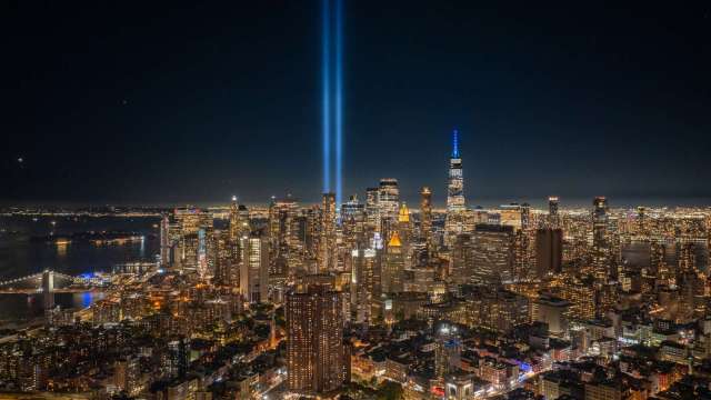 An aerial view of a city skyline at night with two beams of light shining upwards.