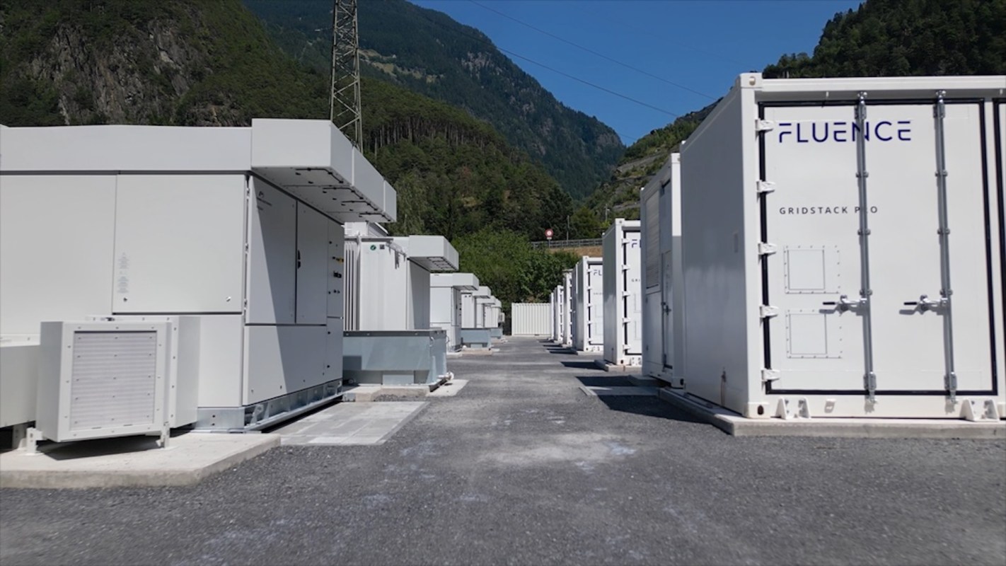 A row of energy storage containers in a mountainous outdoor setting.