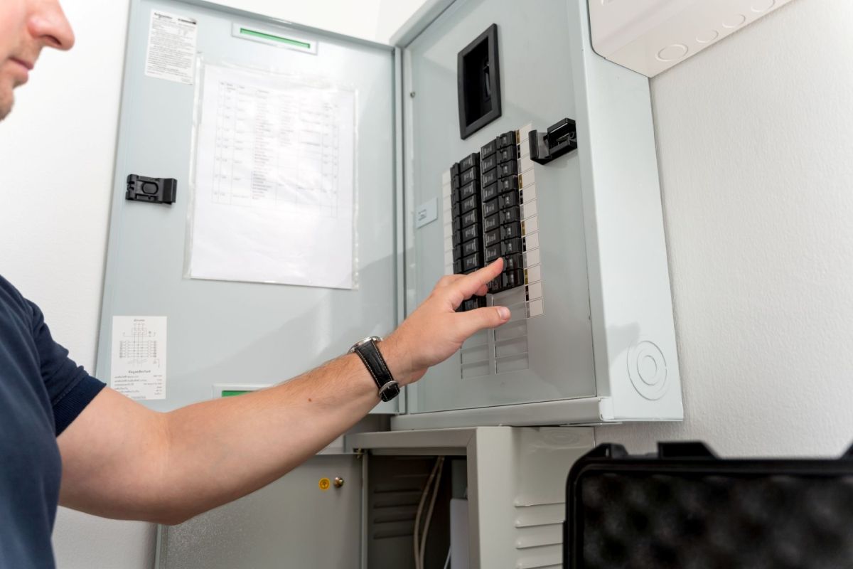 A man flips a breaker in a breaker box