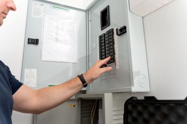 A man flips a breaker in a breaker box
