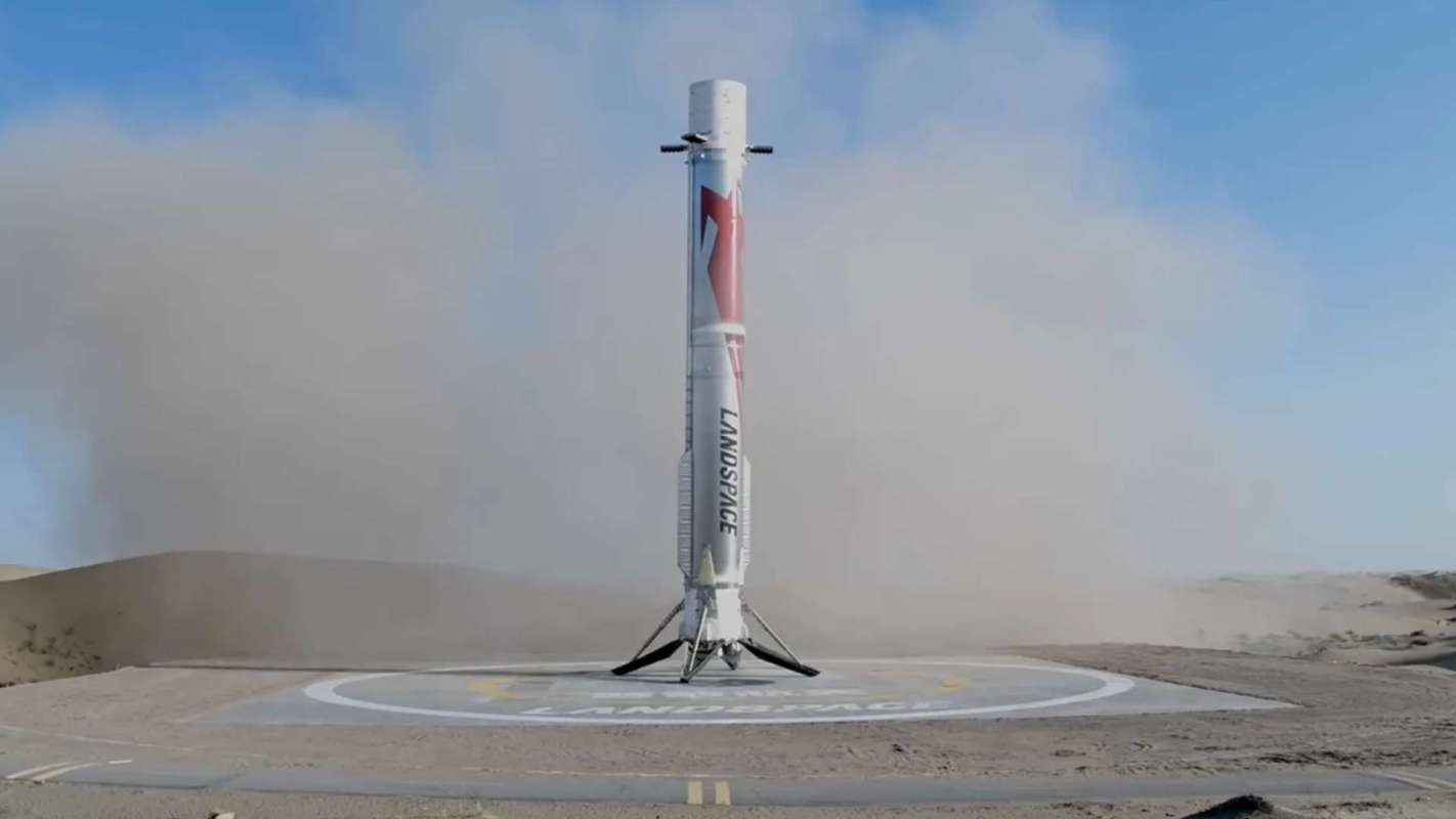 A rocket stands on a landing pad amid dust clouds in a barren landscape.