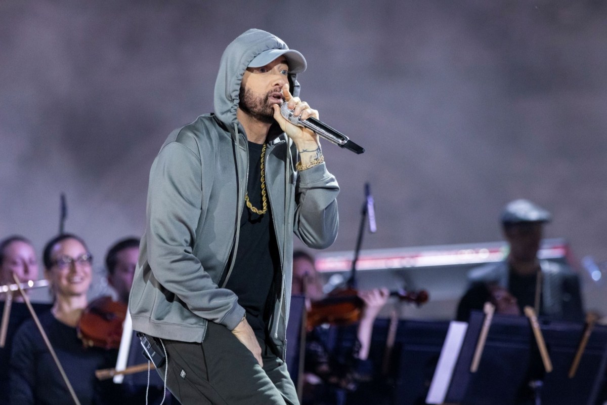 Rapper Eminem raps on stage at a show with musicians behind him