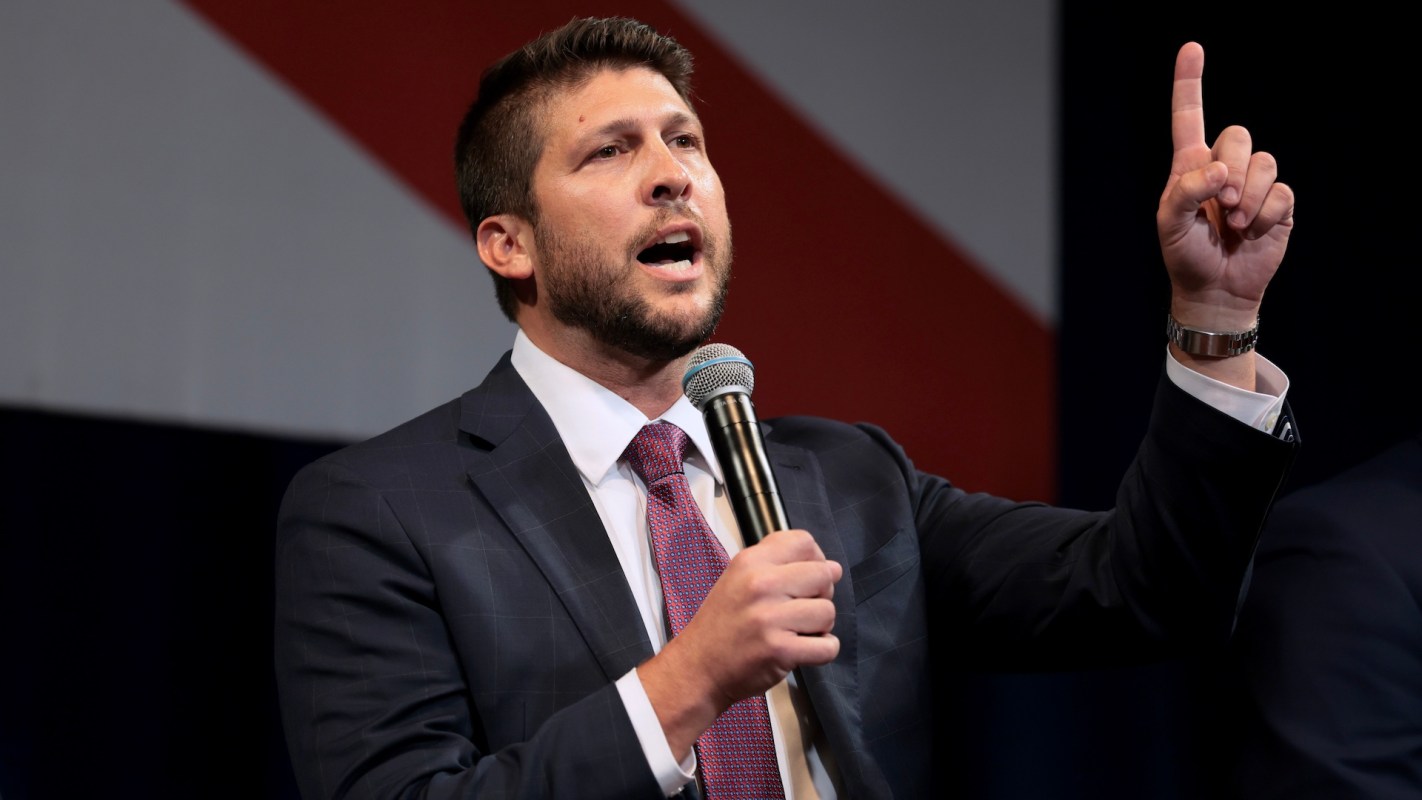 Florida Attorney General James Uthmeier gestures with one hand while holding a microphone during an event.