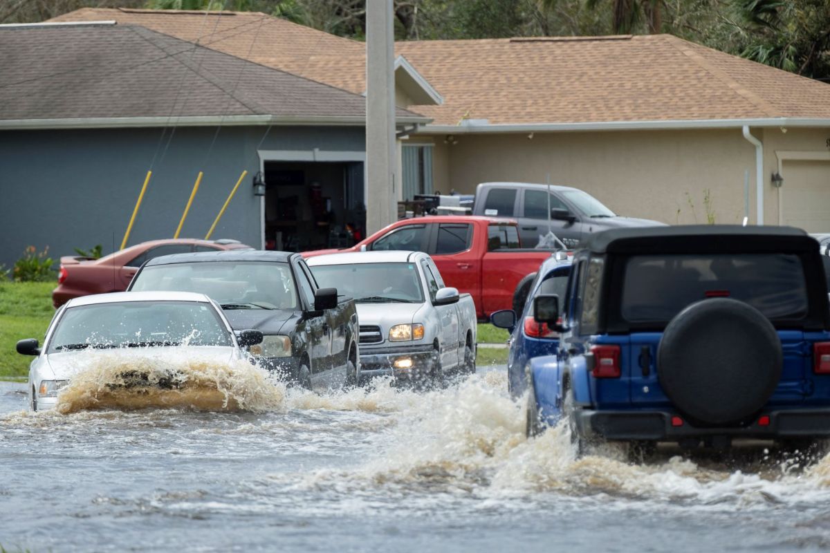 Cars drive through a flooded neighborhood street in Florida