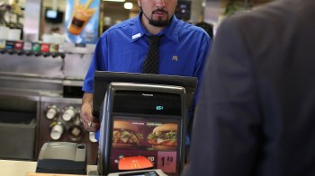 An employee at a McDonald's restaurant assists a customer at the register.