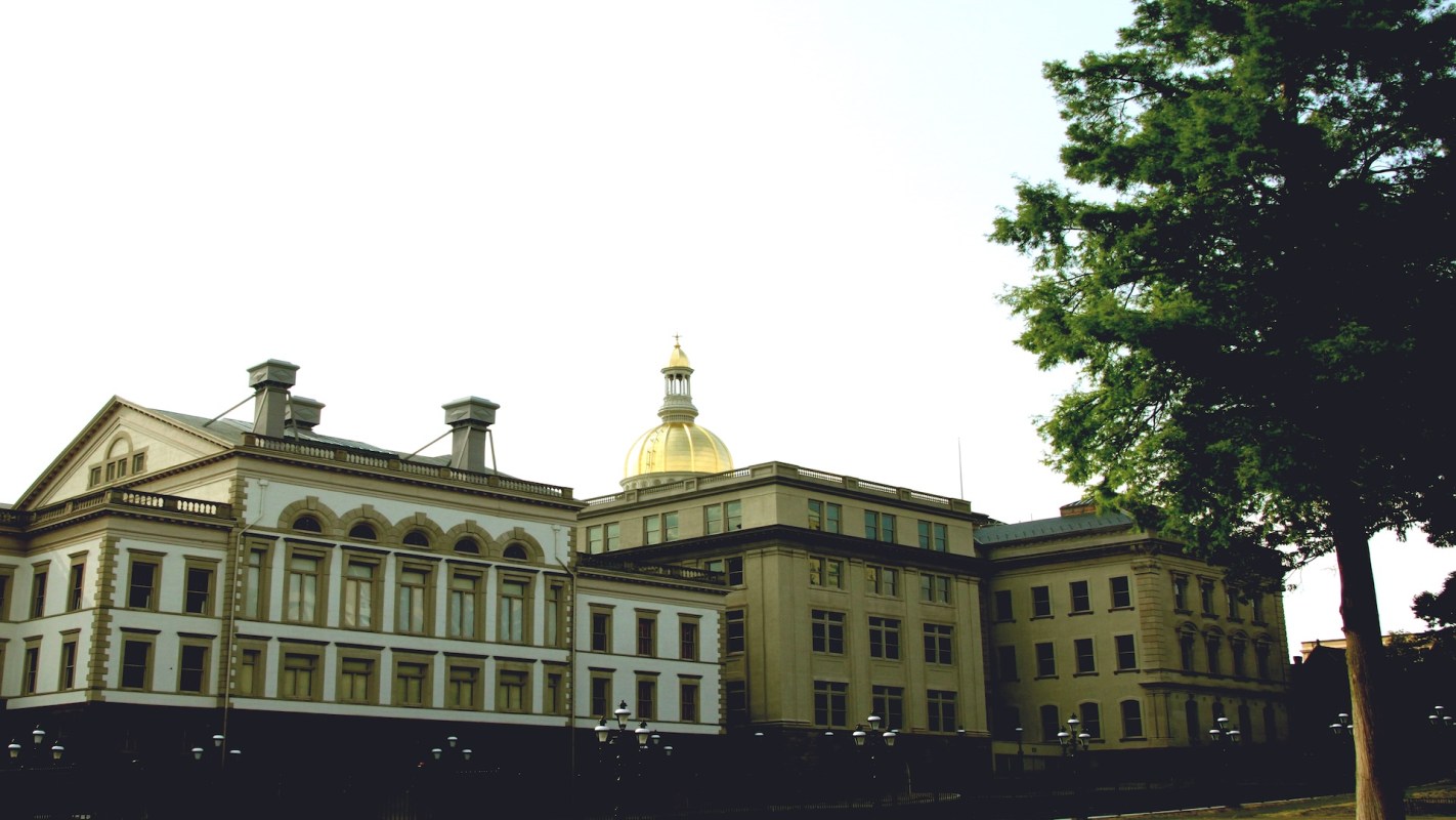 A historic building with a golden dome and a large tree nearby.